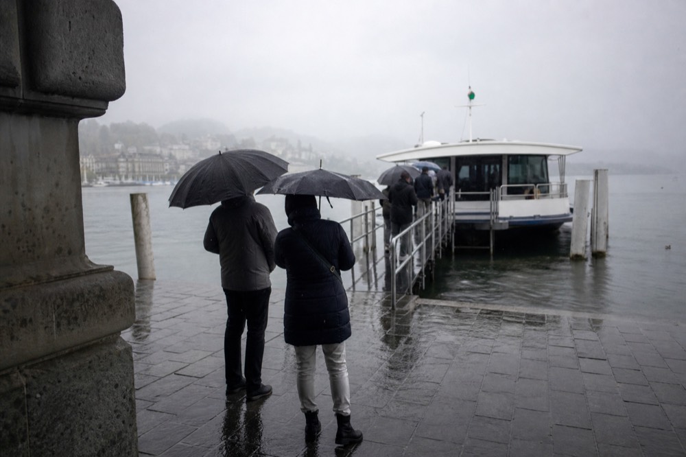 A paddle steamer crossing Lake Lucerne under a soft rainy sky with mist on the hillsides, no text, no logos, no people.