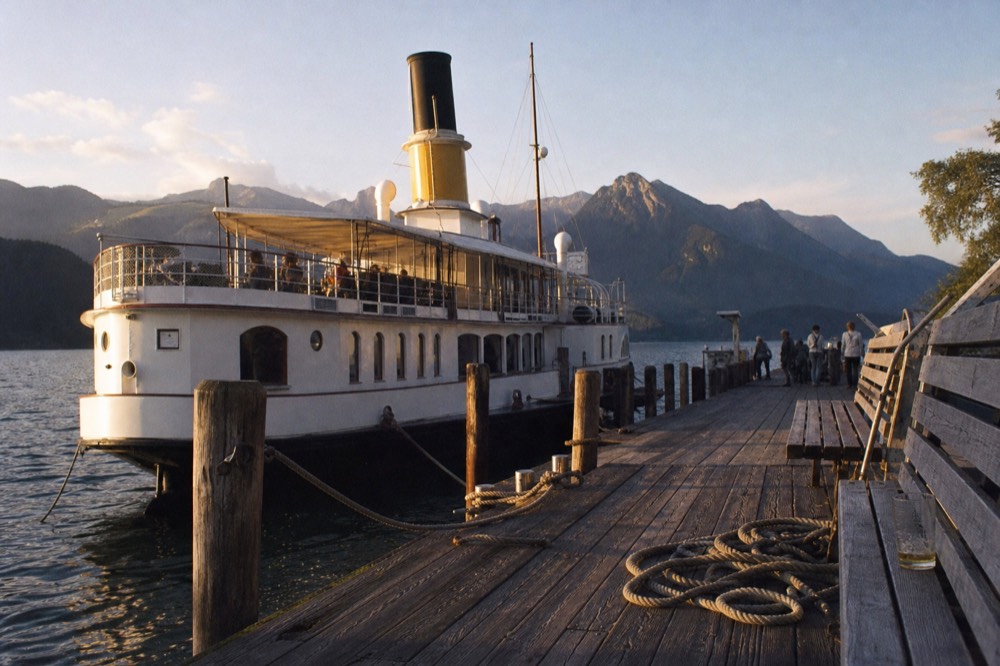 A paddle steamer moored at a wooden pier on Lake Lucerne at golden hour, no text, no logos, no people