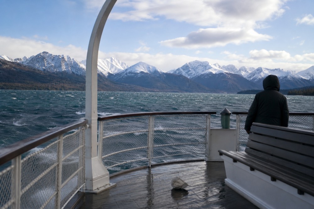 A paddle steamer underway on open water with mountains behind it, no text, no logos, no people.